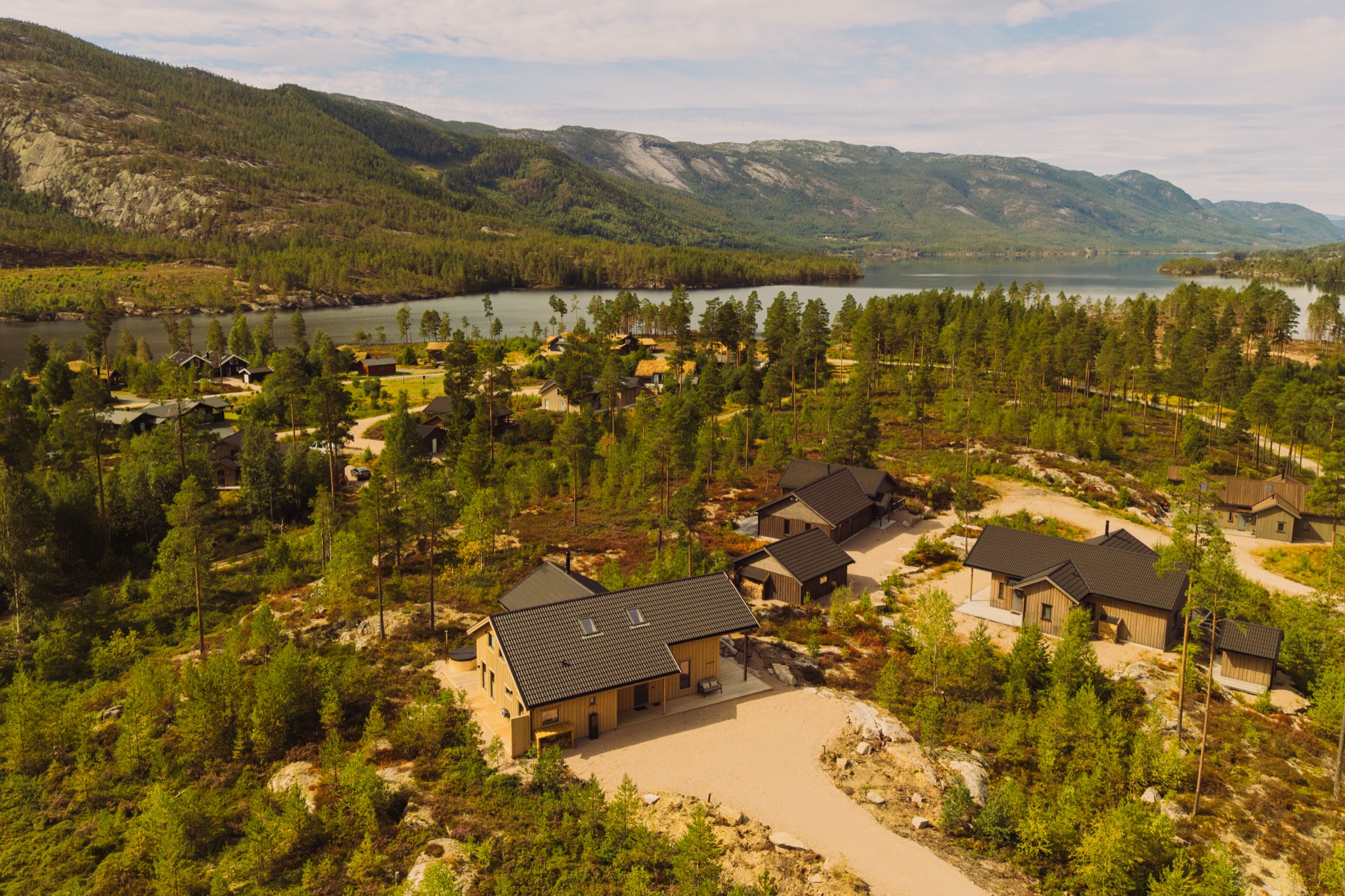 Luchtfoto van Villa Hygge tussen de bomen, met het meer en de bergen van Vrådal op de achtergrond