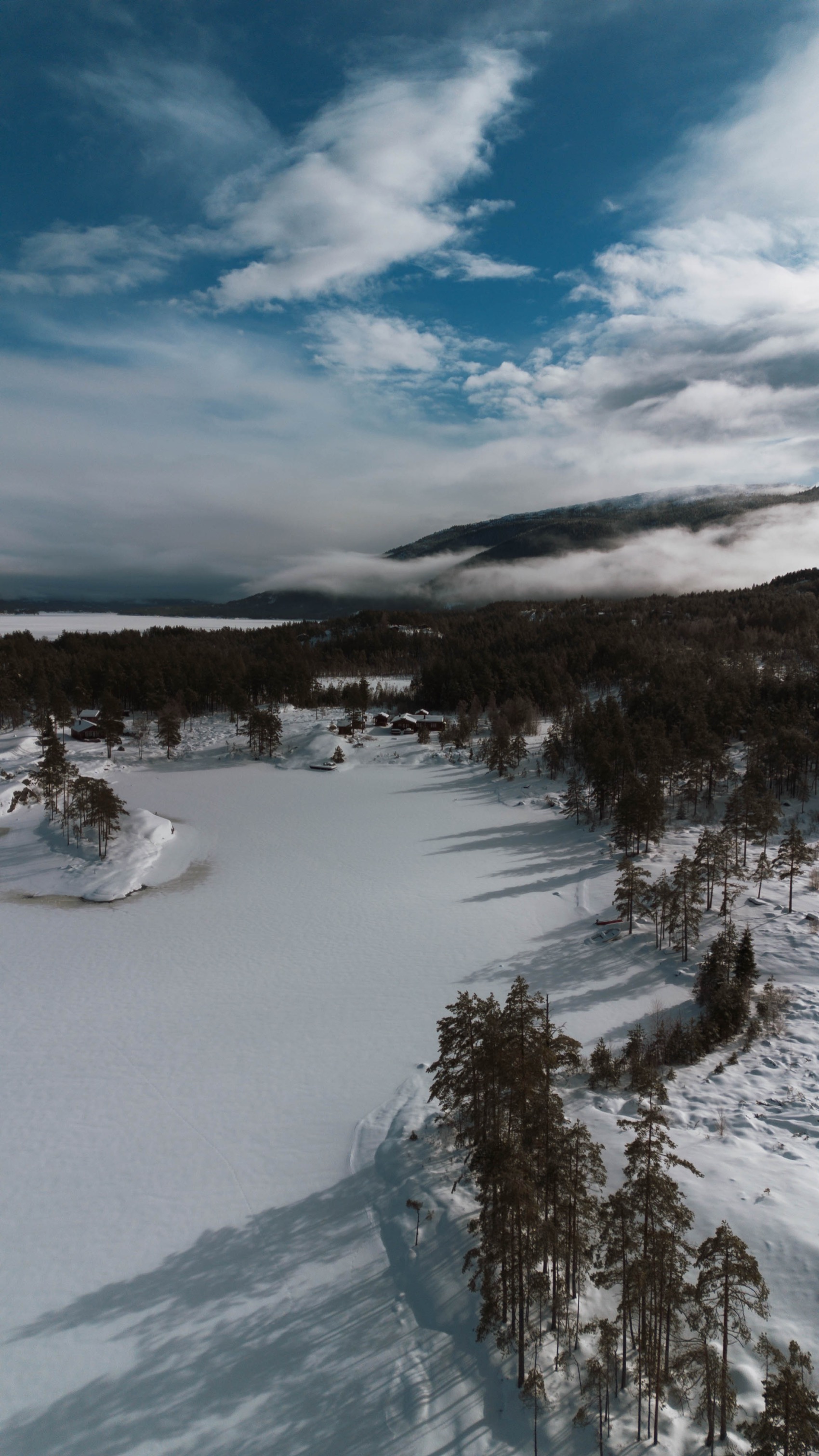 Luchtfoto van een bevroren meer tussen besneeuwde bossen en bergen in Vrådal